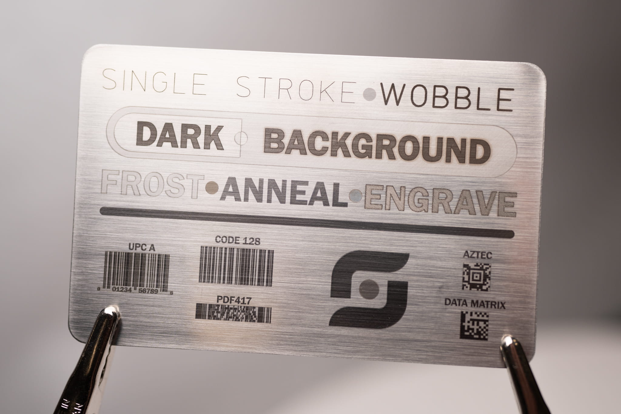 Laser marked stainless steel card showing barcodes, Data Matrix, and Aztec codes